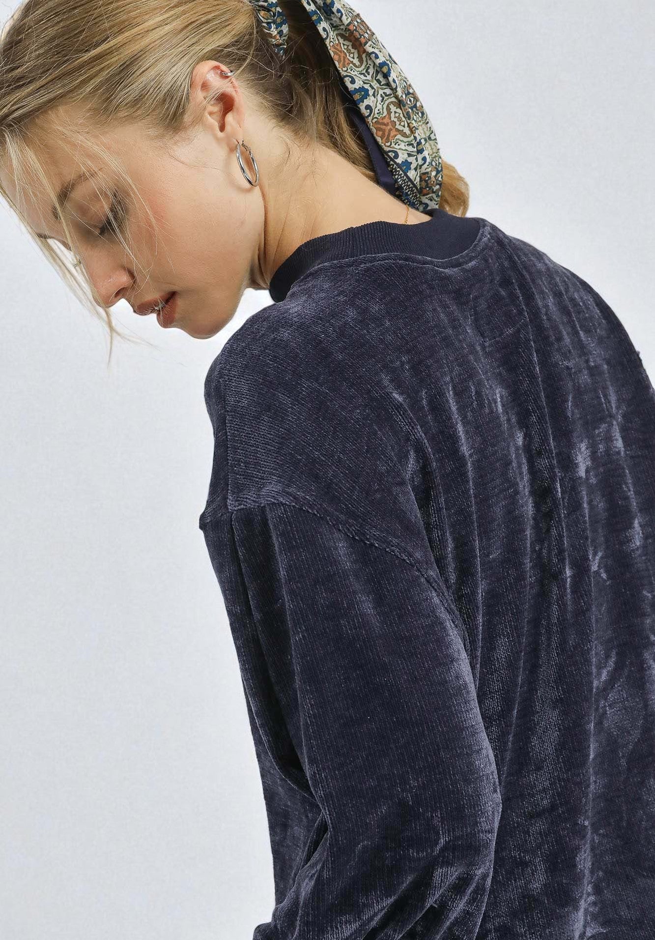 Person wearing a dark blue velvet jacket on a light gray background