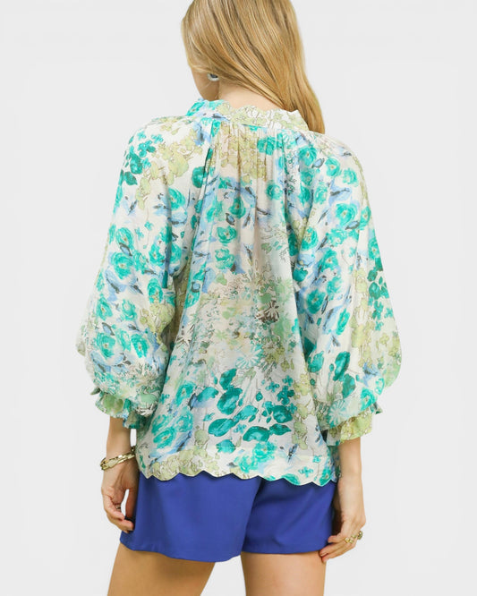 Woman wearing a floral blouse and blue shorts on a white background