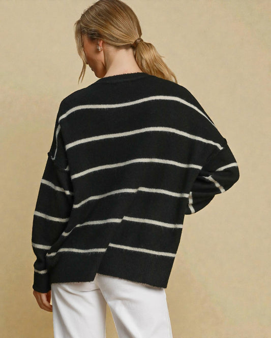 Person wearing a black and white striped sweater on a beige background