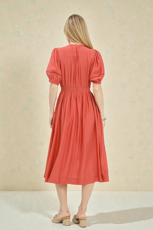 Woman wearing a coral dress against a beige background