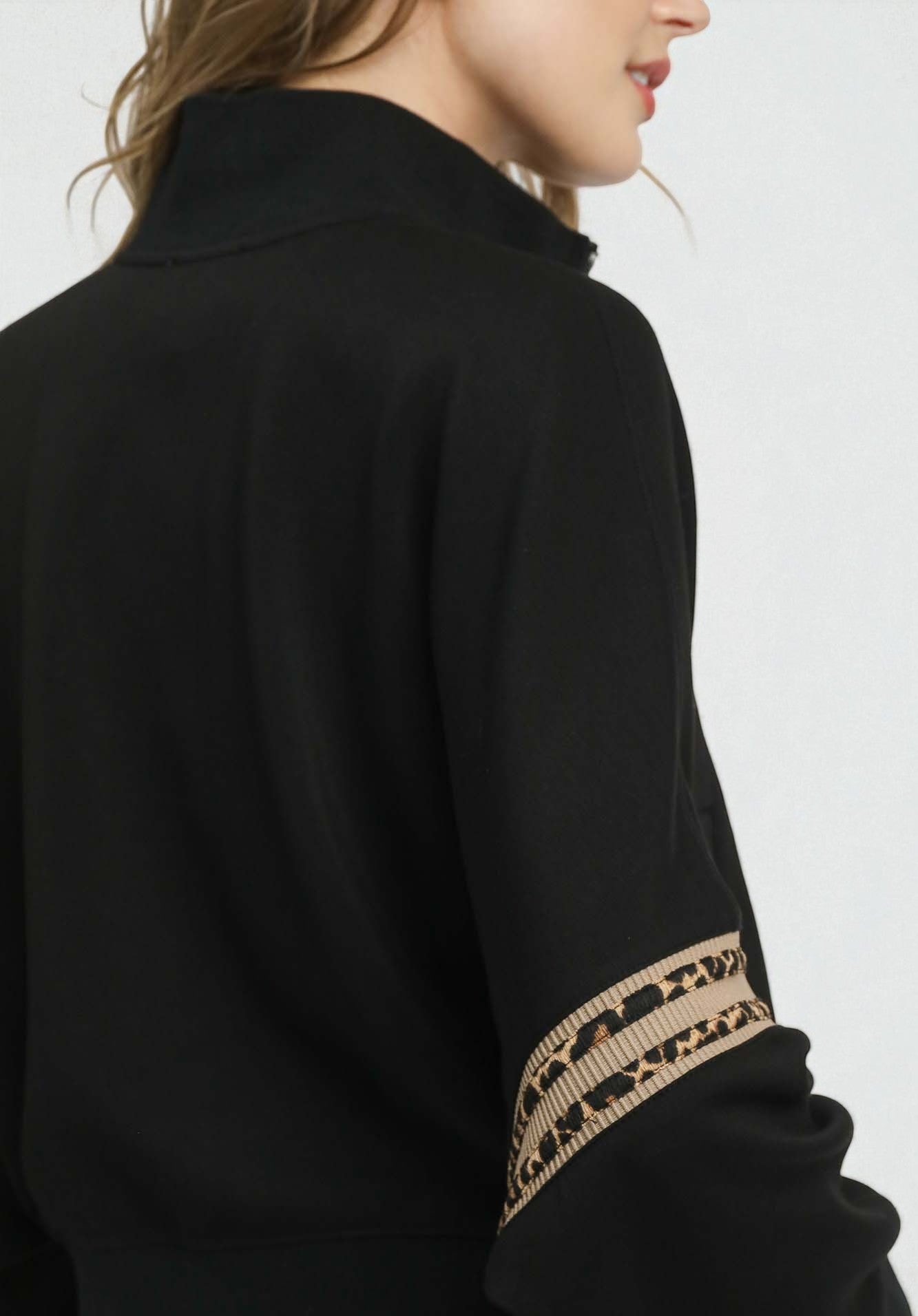 Black coat with gold embroidery on sleeve against a white background
