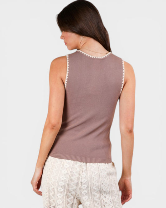 Woman wearing a sleeveless brown top with lace trim on a white background