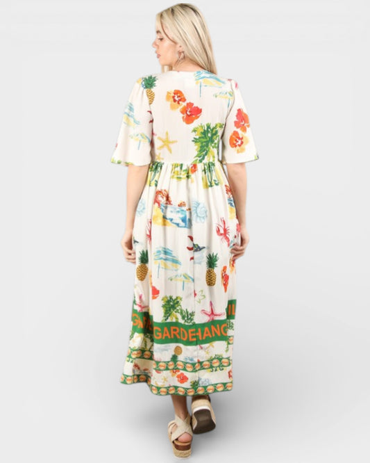 Woman wearing a colorful dress with floral and pineapple patterns on a white background