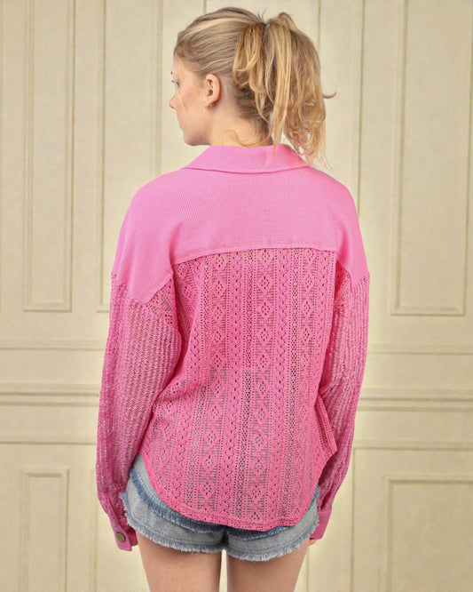 Woman wearing a pink shirt with lace detailing on a beige wall background