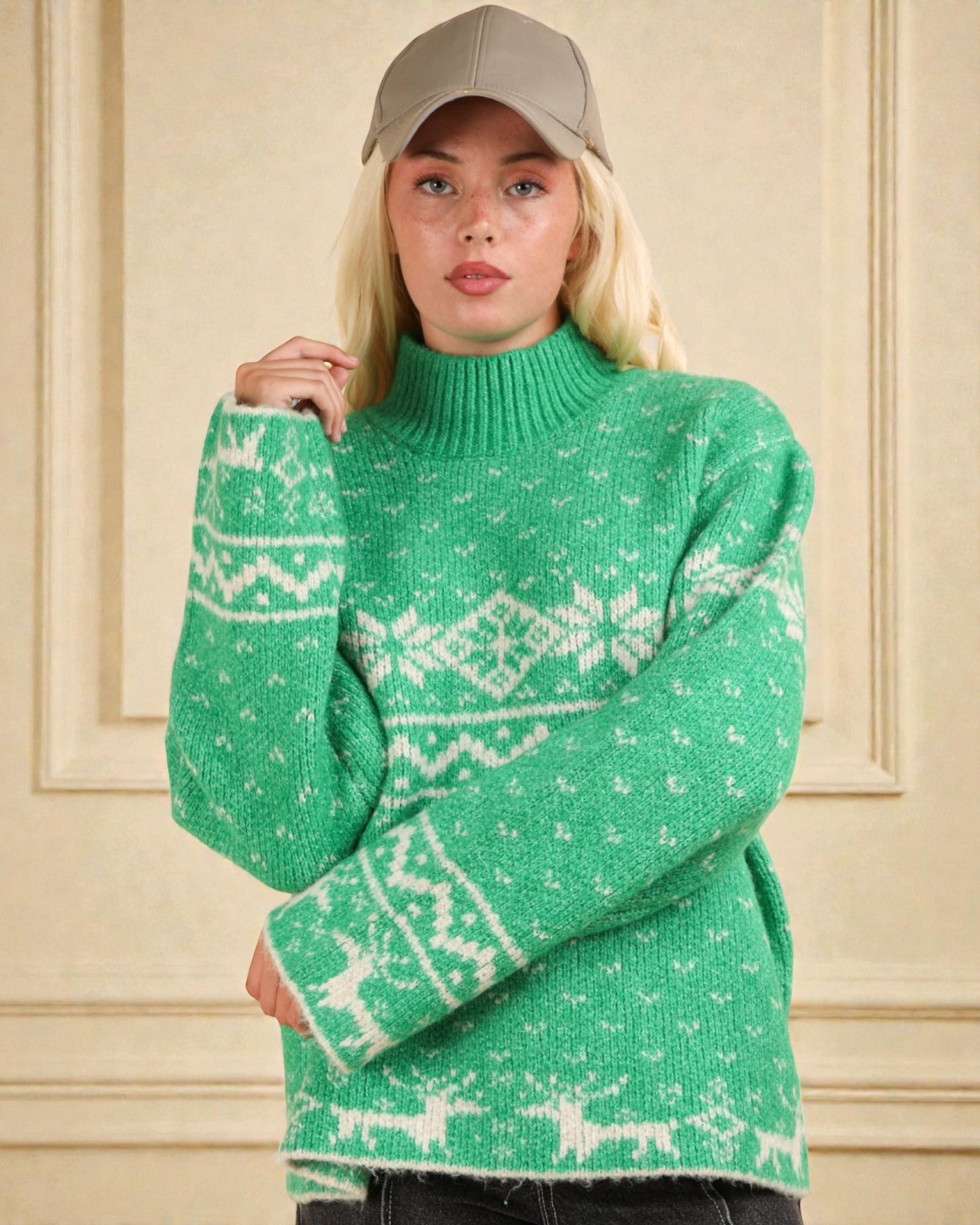 Person wearing a green sweater with white patterns against a beige wall.