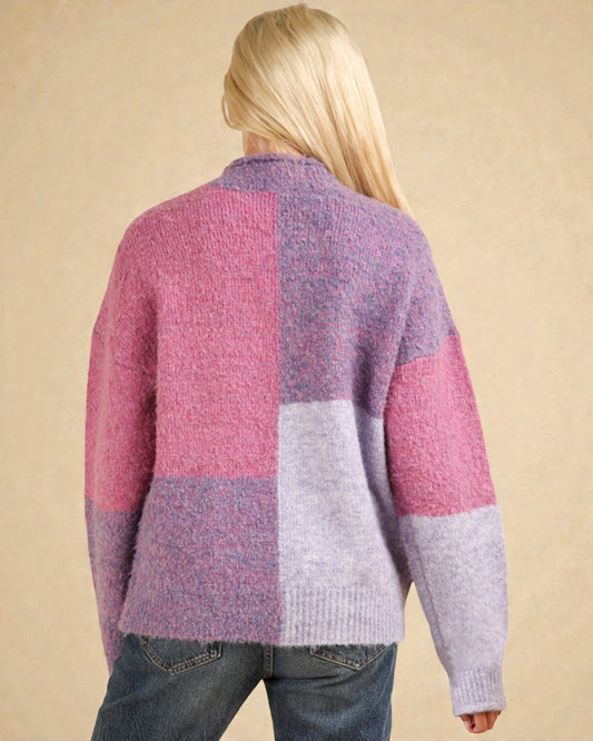 Person wearing a colorful patchwork sweater against a beige background