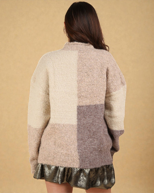 Person wearing a patchwork sweater with a plain background