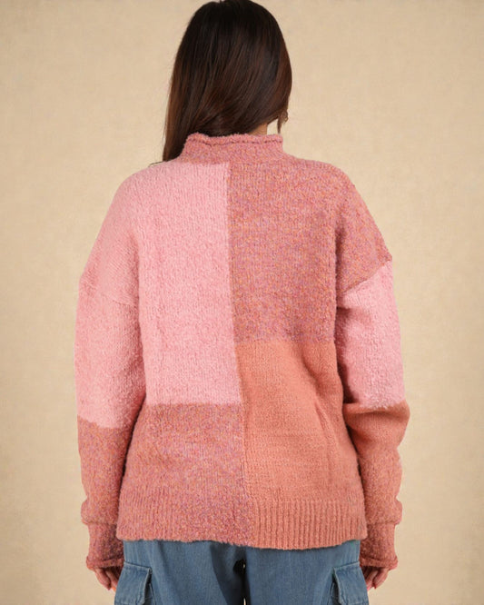 Person wearing a pink and peach color-blocked sweater against a beige background