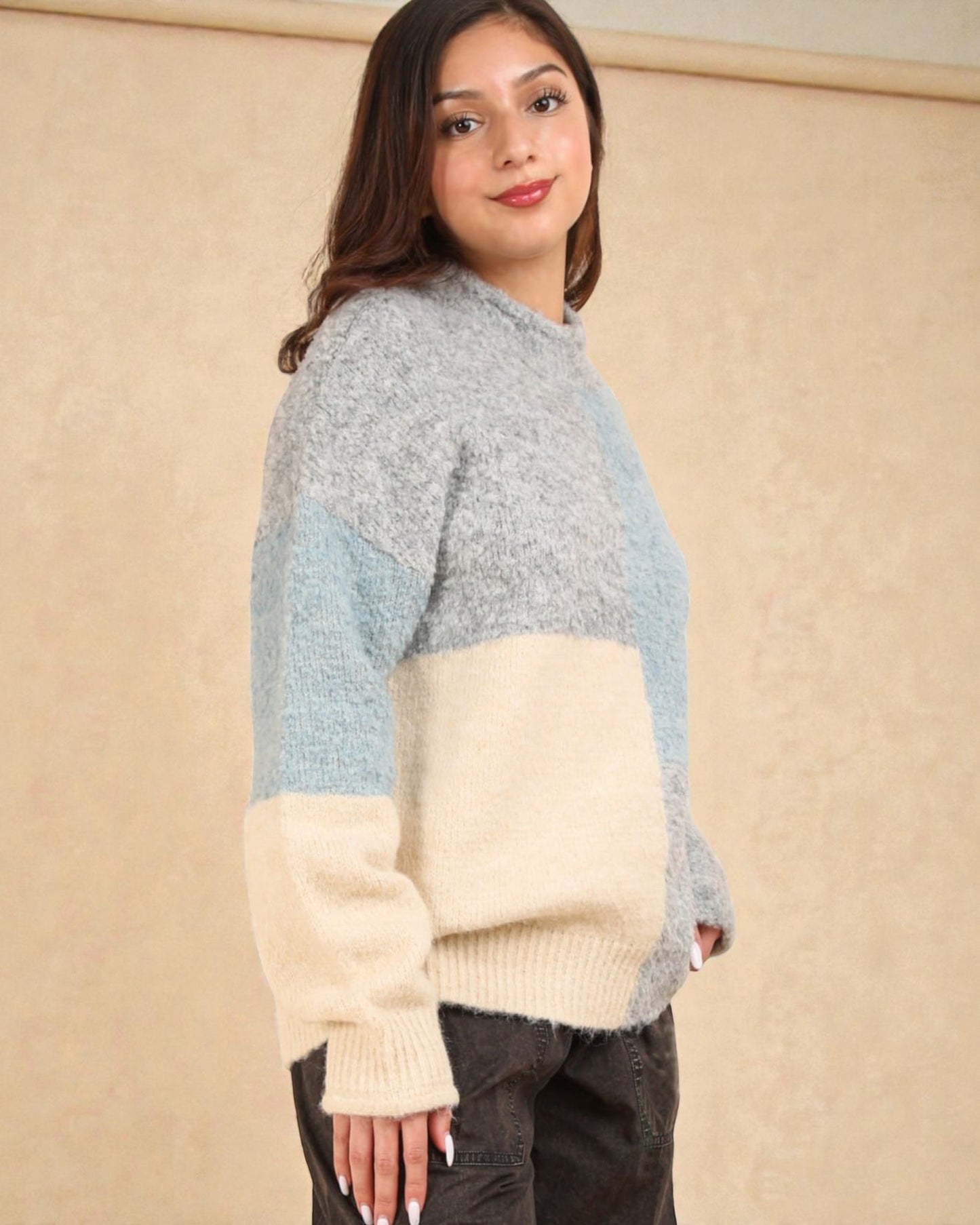 Woman wearing a color-blocked sweater against a beige background