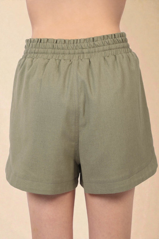 Green shorts worn by a person on a beige background