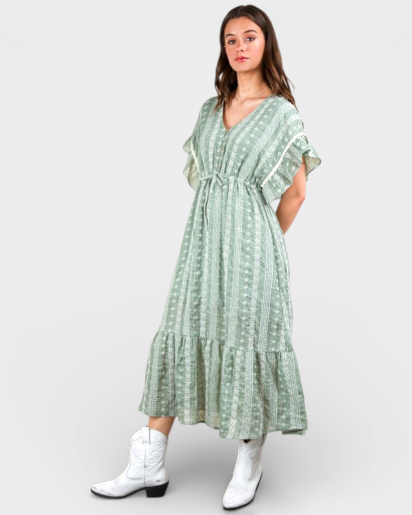 Woman wearing a green patterned dress with white boots on a white background