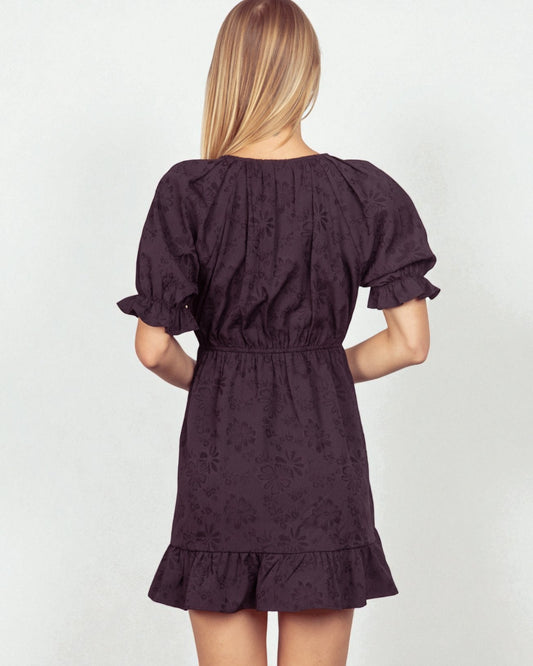 Woman wearing a dark purple dress with puff sleeves on a white background