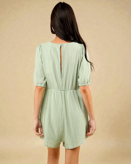 Woman wearing a light green dress with a plain background