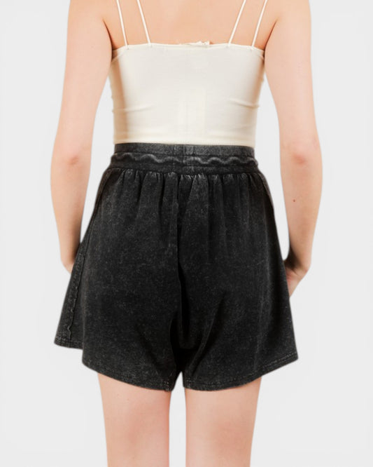 Person wearing a white top and black shorts on a plain background