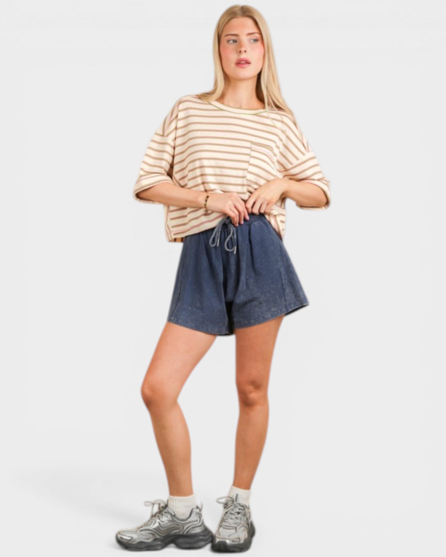 Woman wearing a striped shirt and denim shorts on a white background