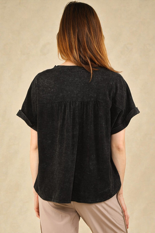 Person wearing a black short-sleeve top against a beige background