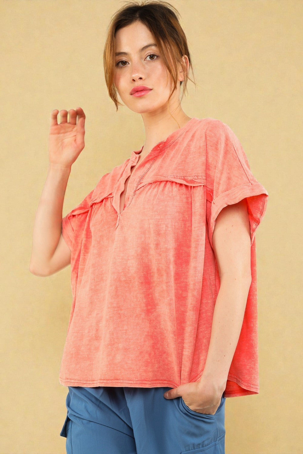 Woman wearing a coral top with a beige background