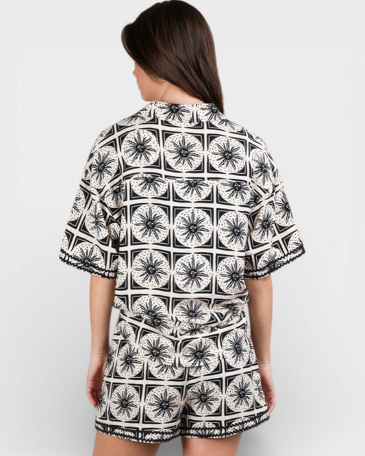 Person wearing a black and white patterned outfit on a plain background