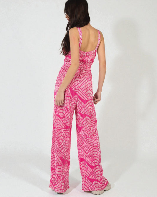 Woman wearing a pink patterned jumpsuit on a white background