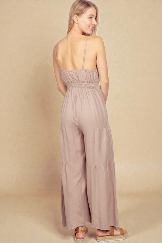 Woman wearing a mauve jumpsuit against a beige background