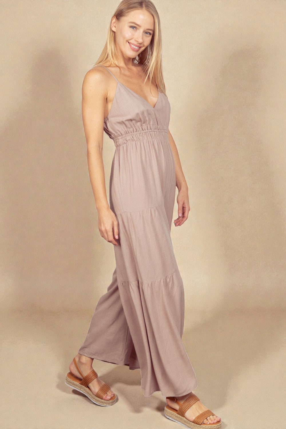 Woman wearing a long, light-colored dress against a beige background