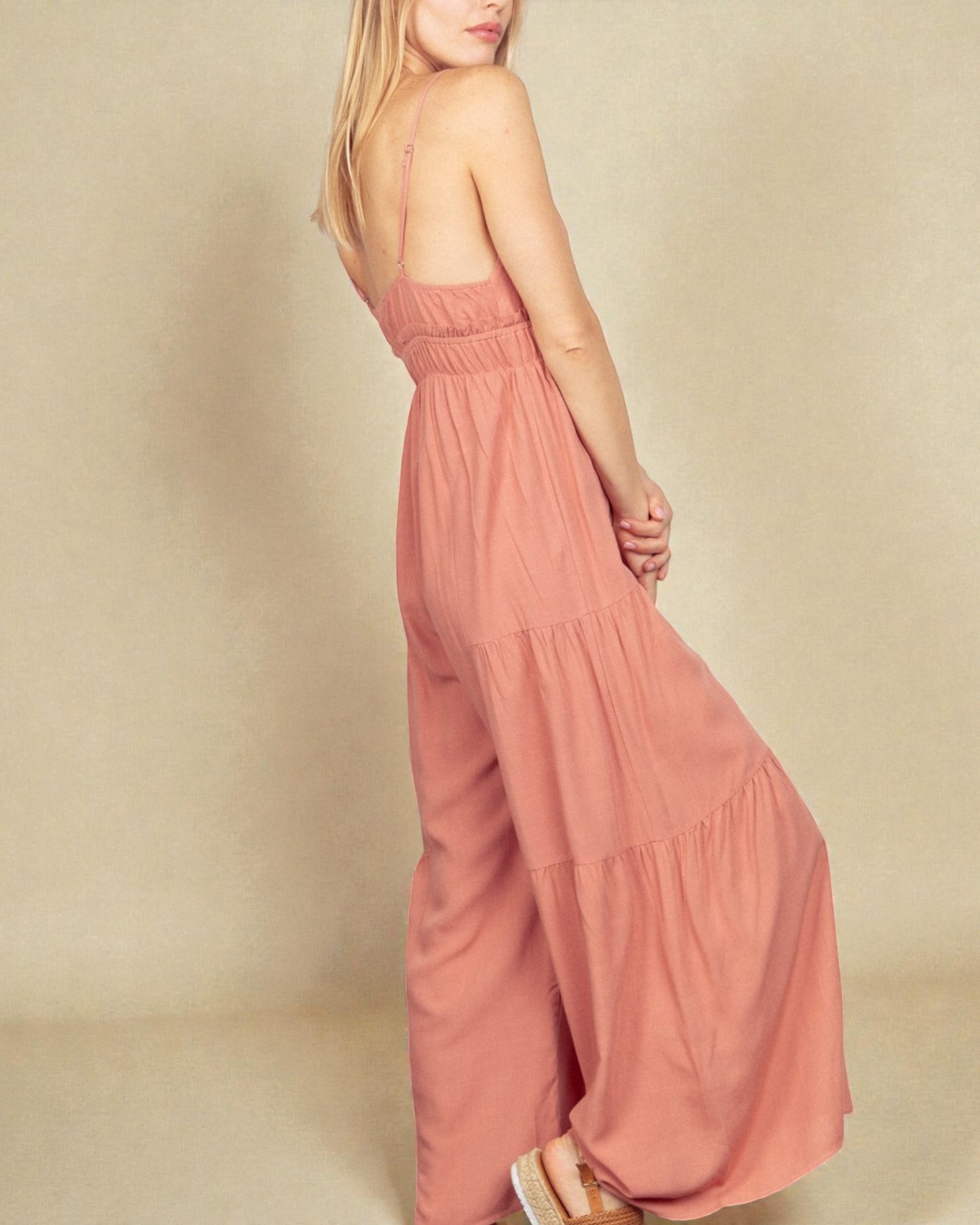 Woman wearing a pink jumpsuit on a beige background