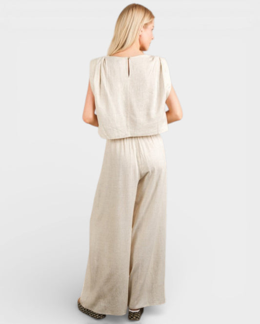 Woman wearing a beige sleeveless top and wide-leg pants on a white background