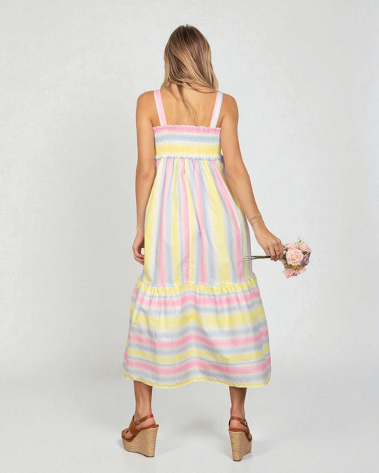 Woman wearing a pastel striped dress holding flowers on a white background