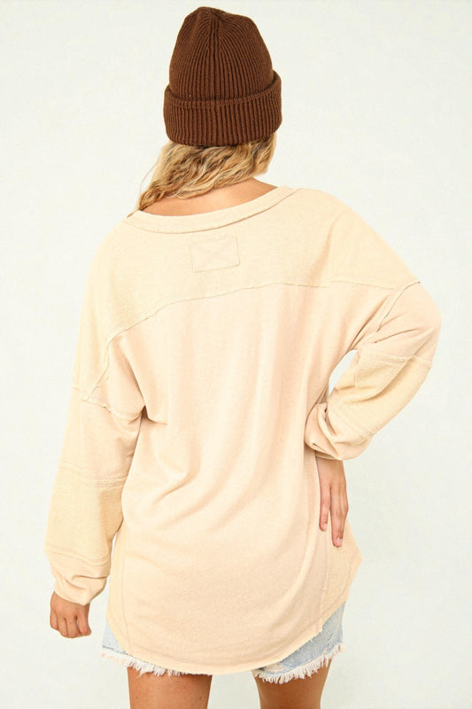 Person wearing a beige oversized sweater and brown beanie on a white background