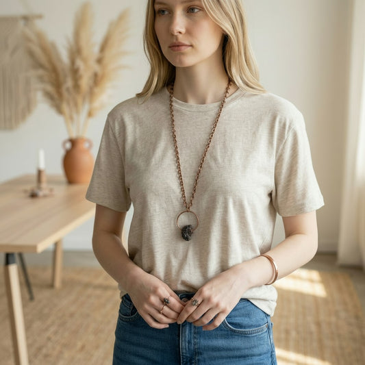 Woman wearing a beige t-shirt and blue jeans indoors with a neutral background