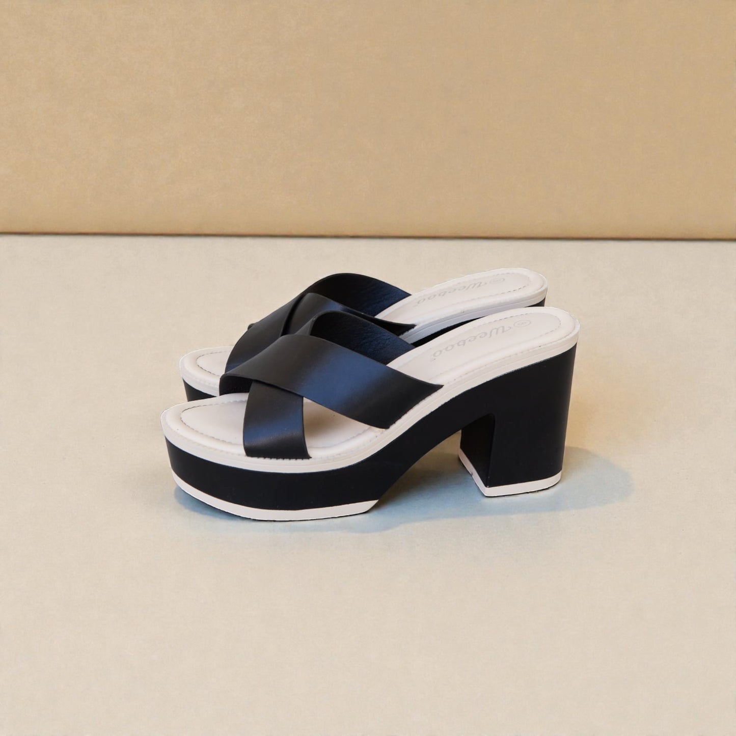 Black platform sandals with white sole on a beige background