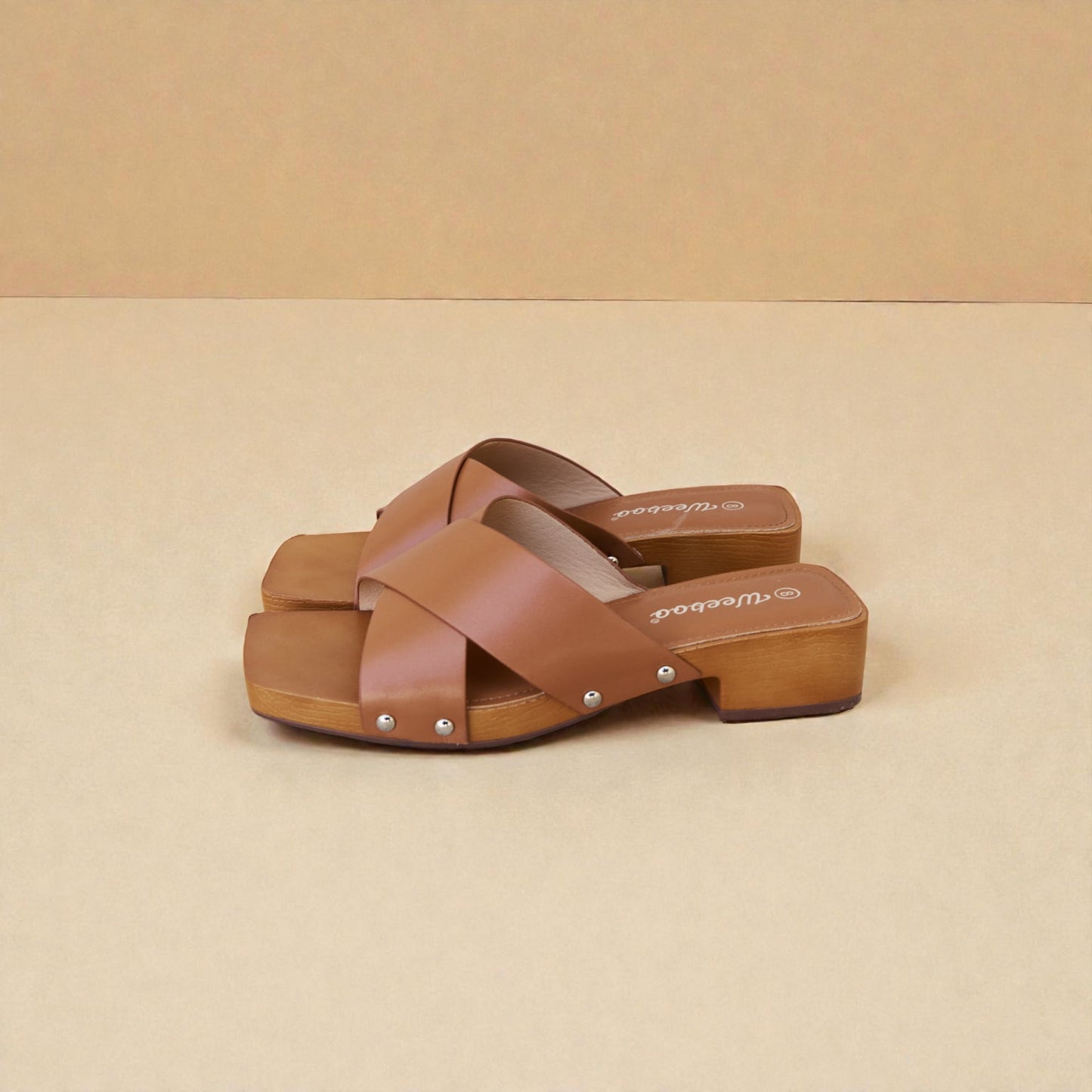Pair of brown sandals with wooden sole on a beige background