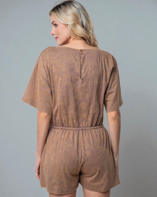 Woman wearing a brown tie-dye romper against a gray background