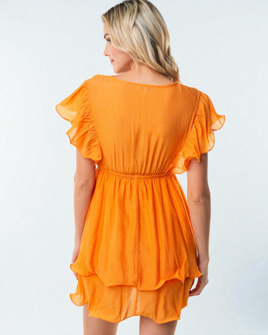 Woman wearing an orange dress with ruffled sleeves on a white background
