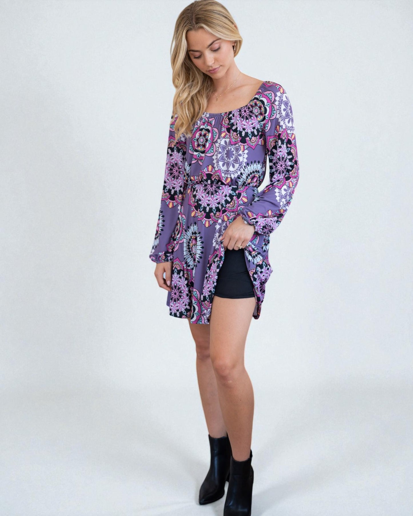 Woman wearing a long-sleeve, patterned dress with a white background