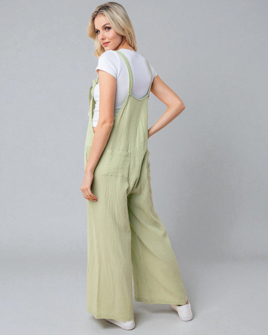 Woman wearing a light green ribbed jumpsuit on a gray background