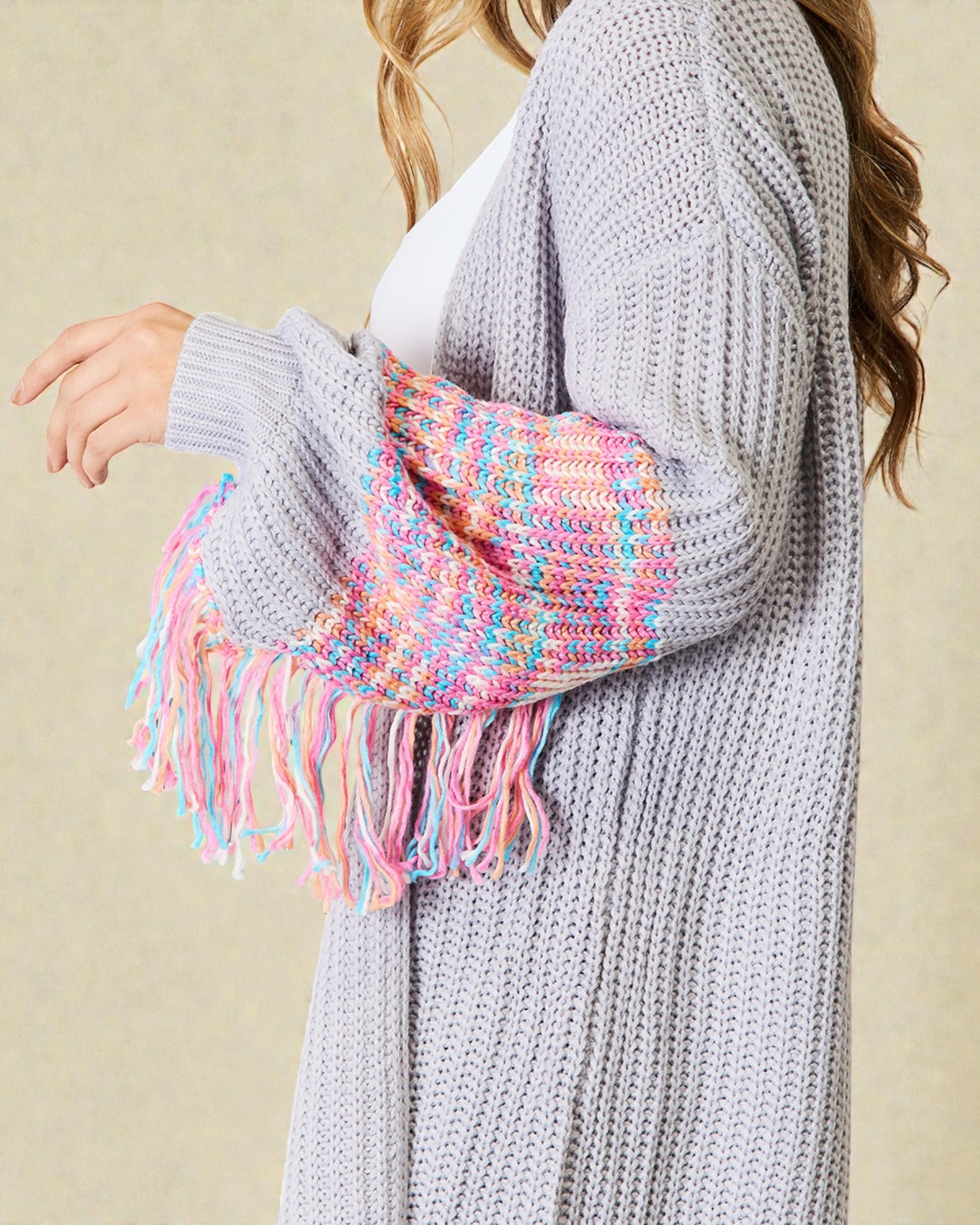 Person wearing a gray knit cardigan with a colorful scarf draped over the shoulder against a beige background