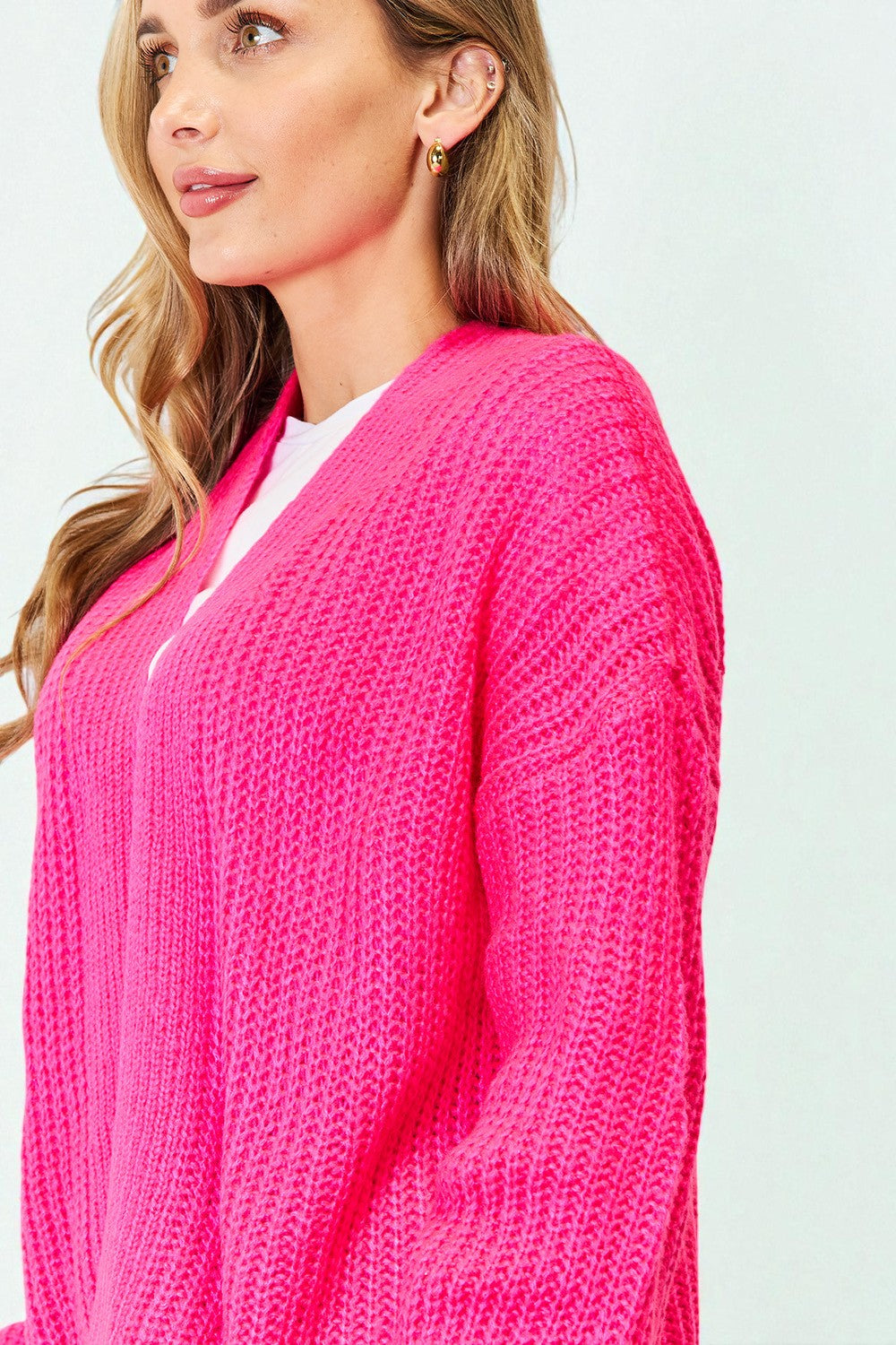 Woman wearing a bright pink cardigan against a light background