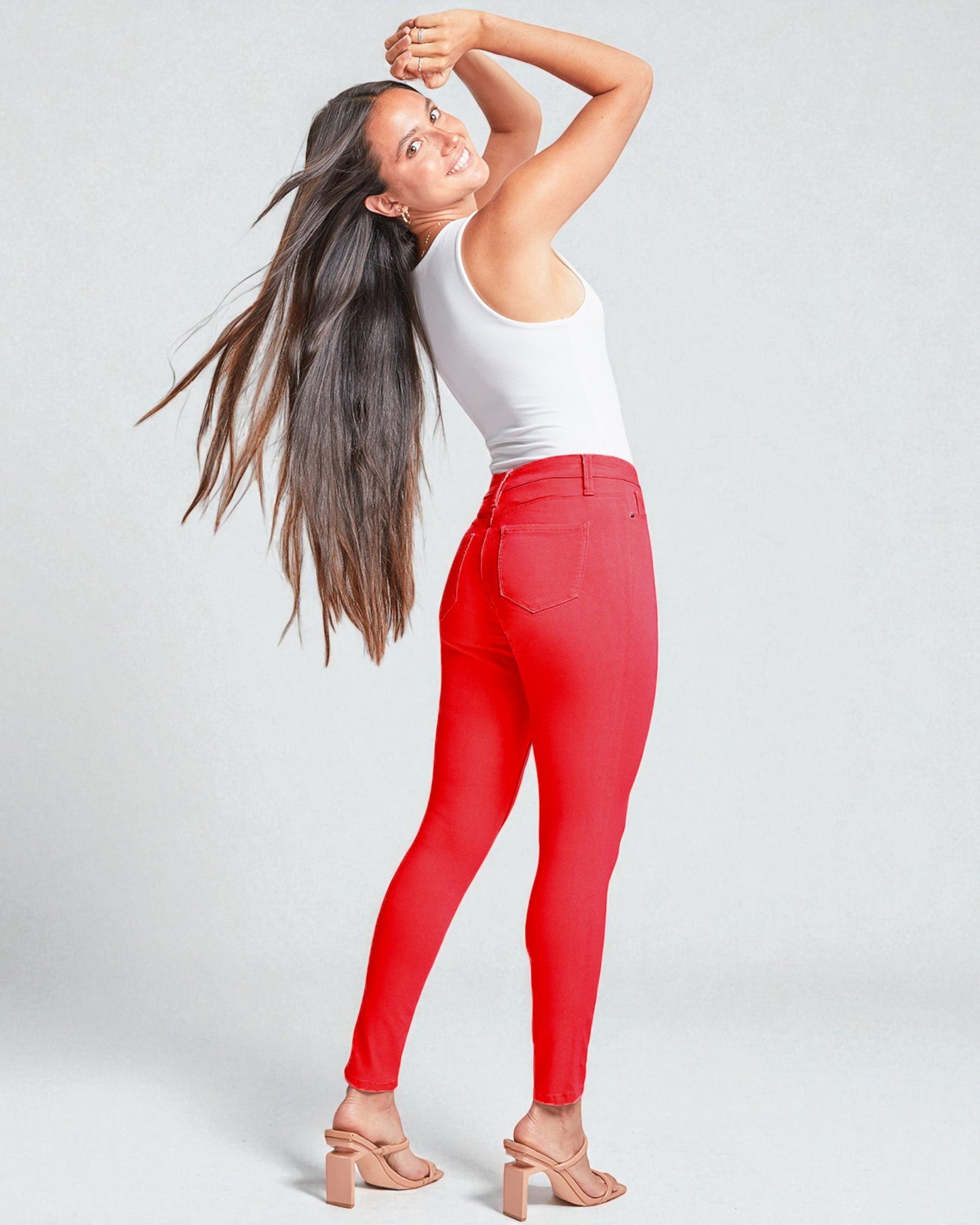 Woman wearing red pants and a white top on a light gray background