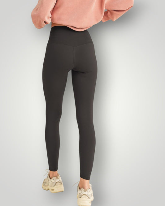 Person wearing black leggings and a pink sweatshirt on a light gray background