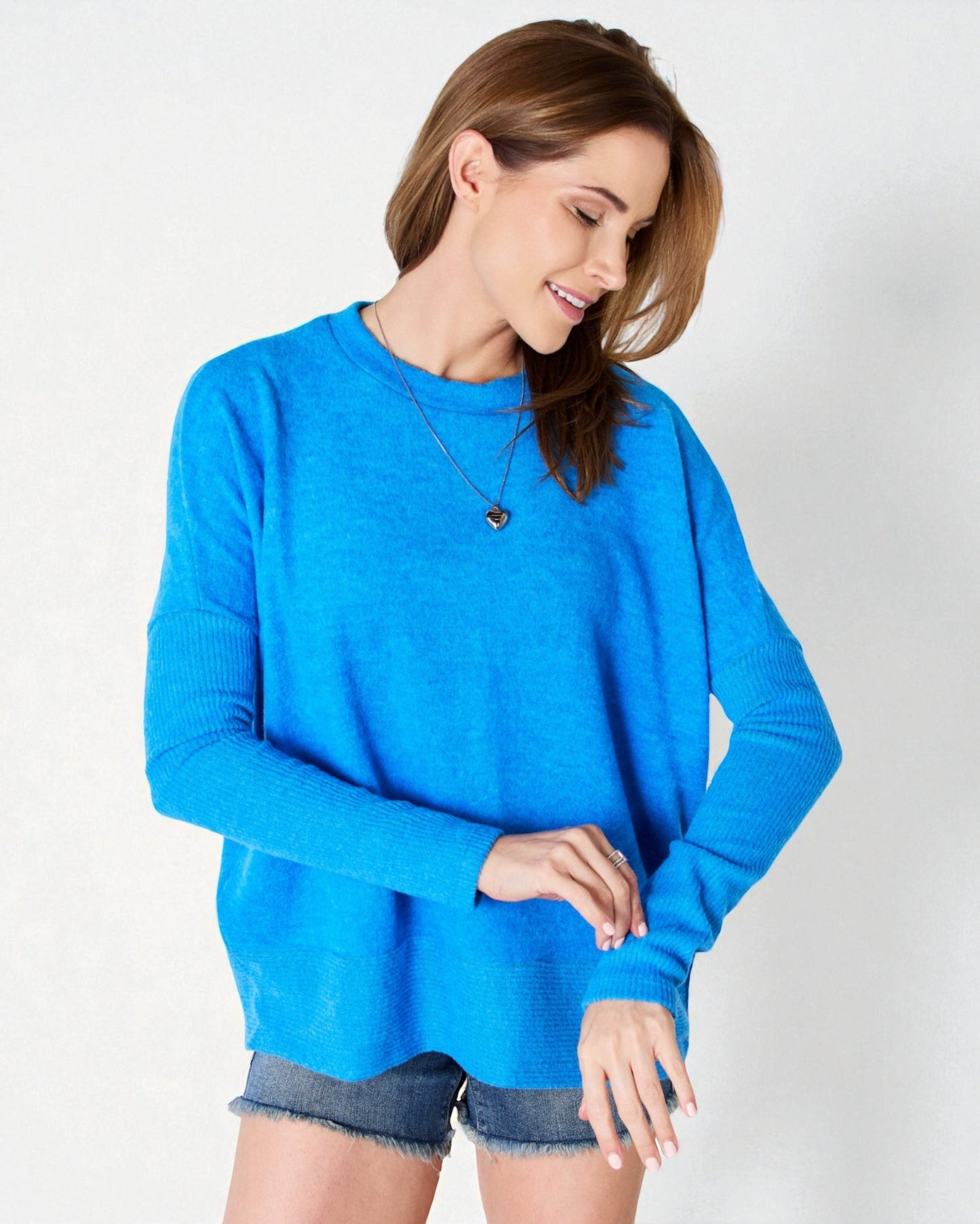 Woman wearing a blue sweater and denim shorts on a white background