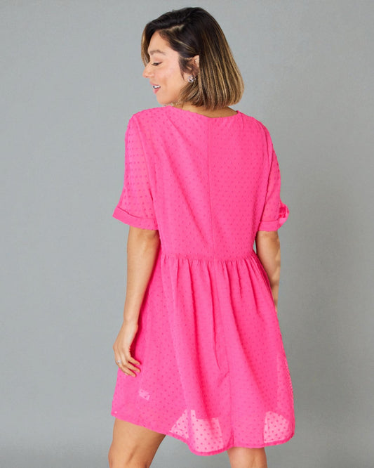 Woman wearing a bright pink dress against a gray background