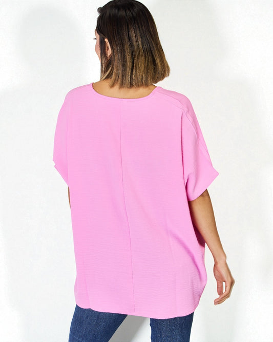 Person wearing a pink oversized top on a white background
