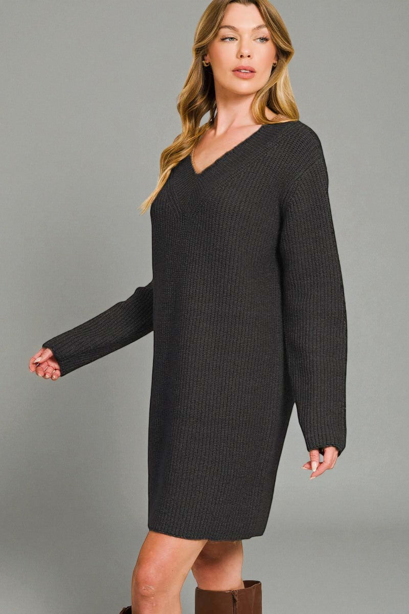Woman wearing a black ribbed sweater dress against a gray background