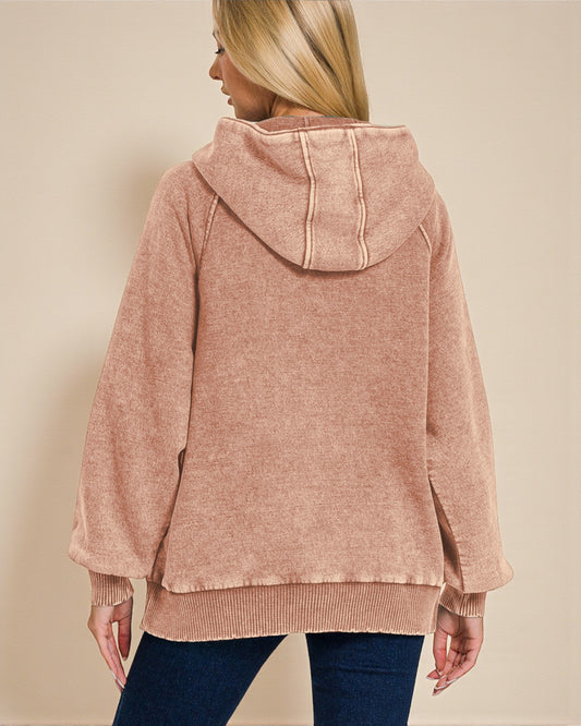 Person wearing a pink hooded sweater against a beige background