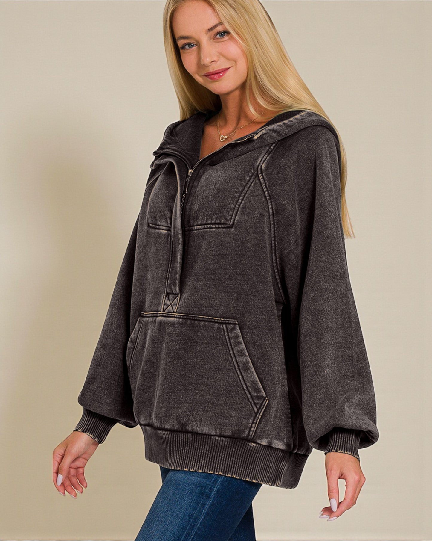 Woman wearing a black distressed hoodie on a beige background