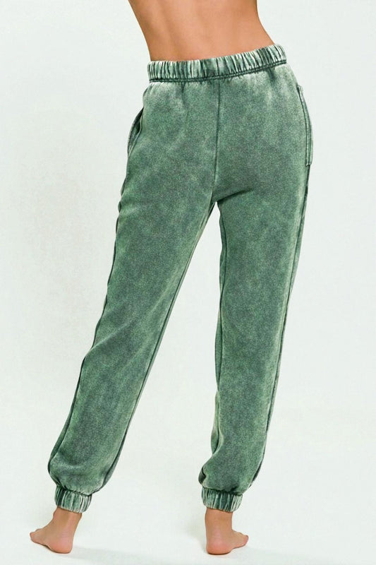 Green sweatpants worn by a person on a white background