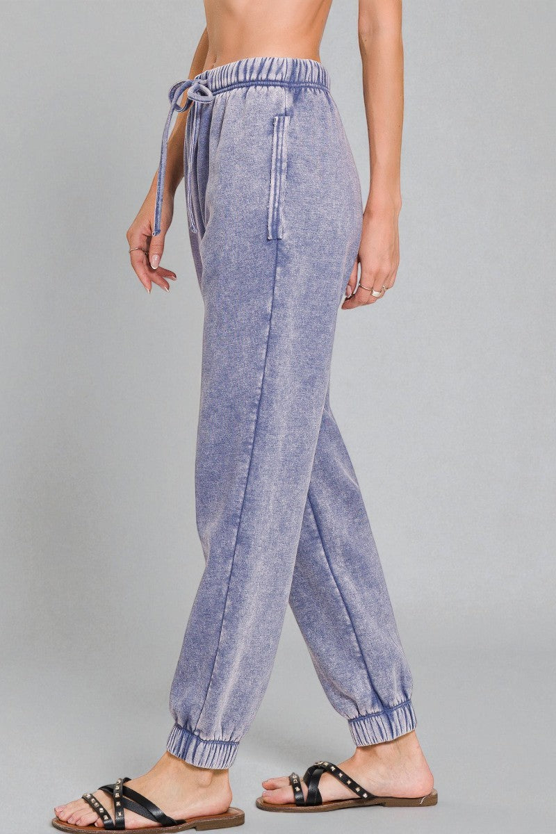 Blue denim jogger pants worn by a person on a gray background