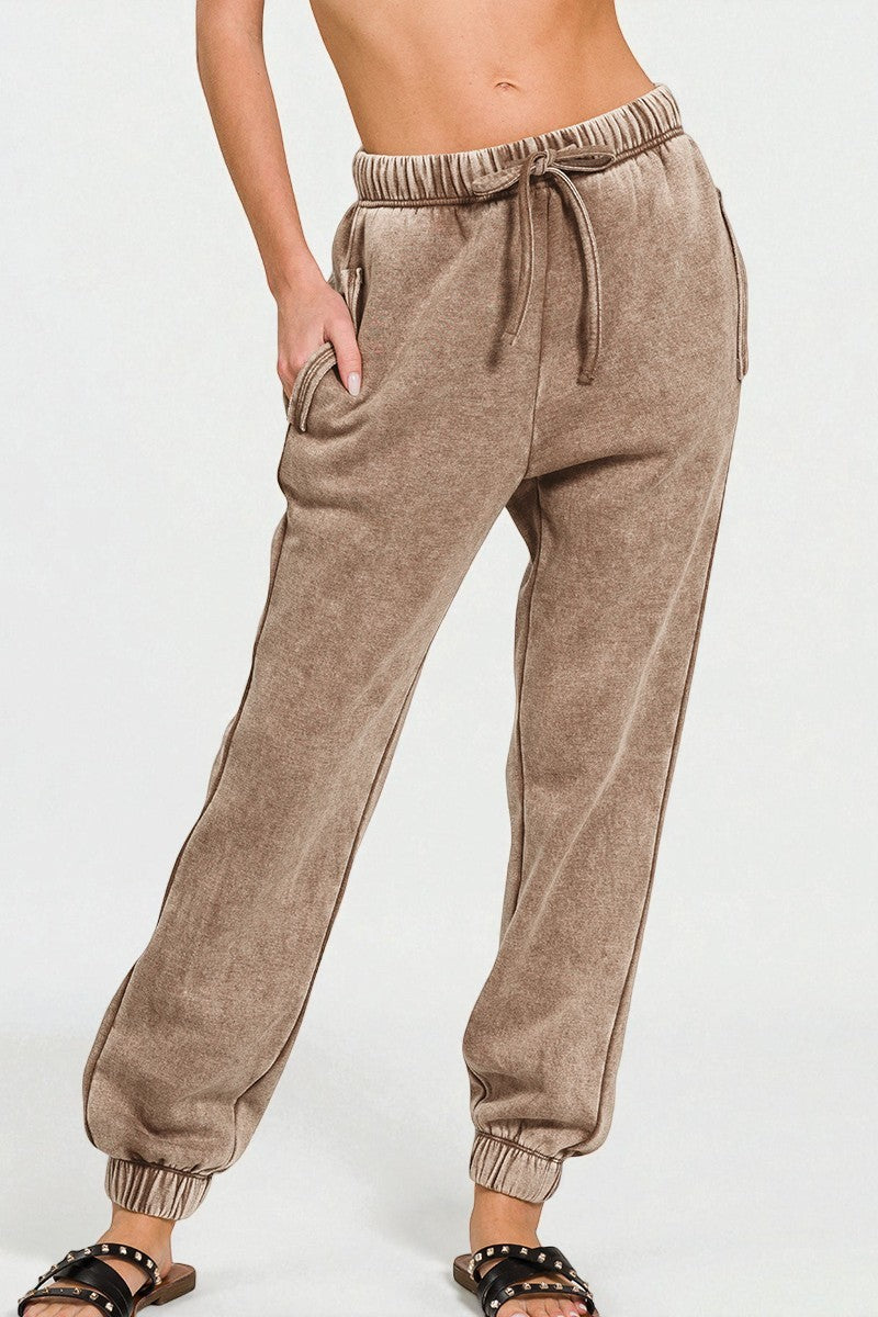 Brown sweatpants worn by a person on a white background
