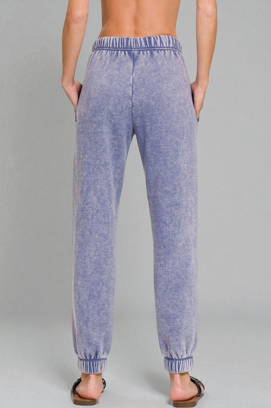 Blue jogger pants worn by a person on a gray background